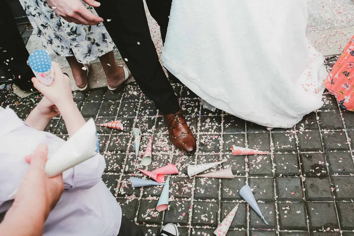 Paper confetti cones scattered on cobbles at the feet of the bride and groom