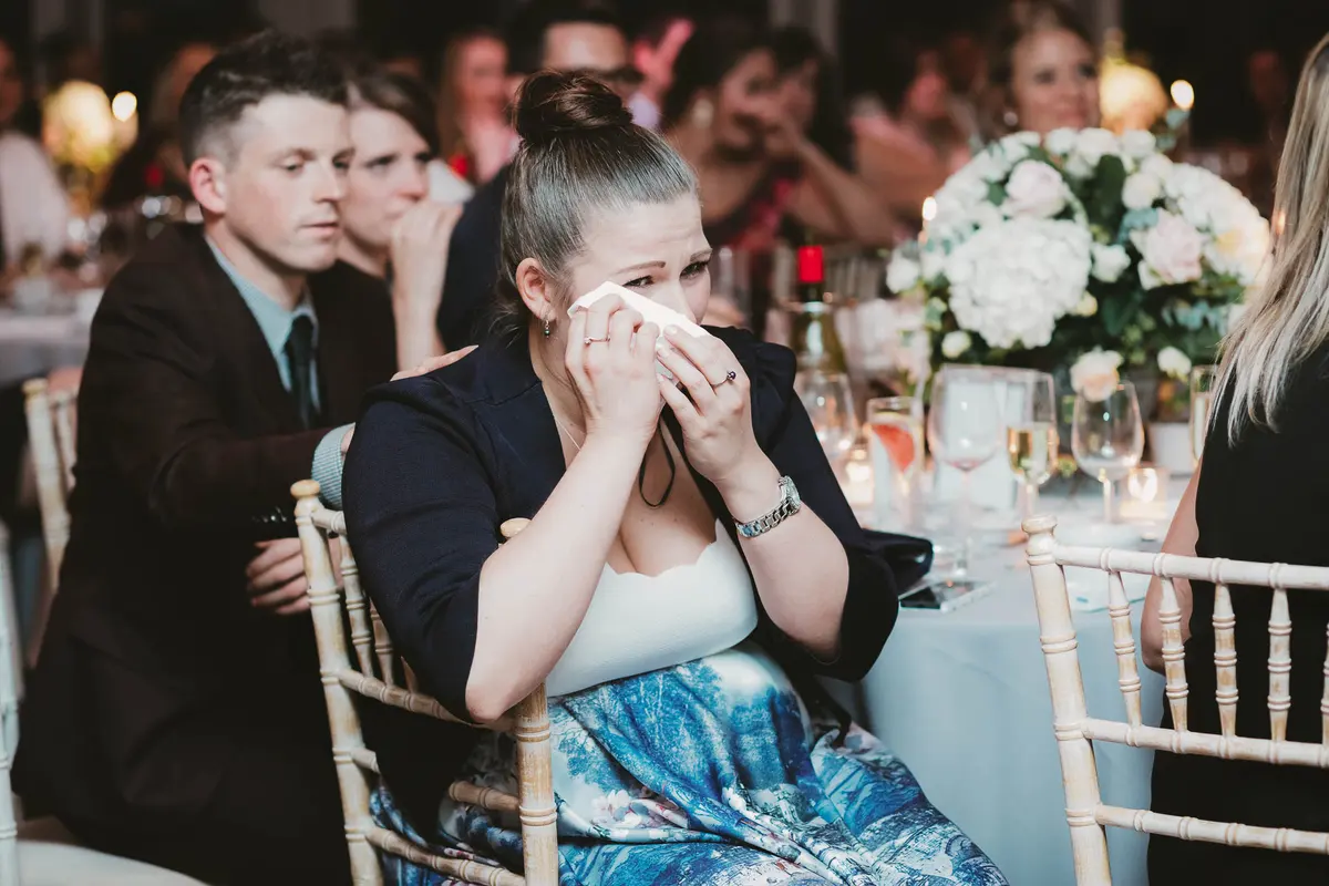 Guest dabbing tears with a tissue during the speeches at a candlelit reception