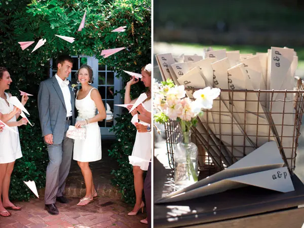 Couple and guests throwing paper aeroplanes, with a basket of monogrammed paper planes beside flowers