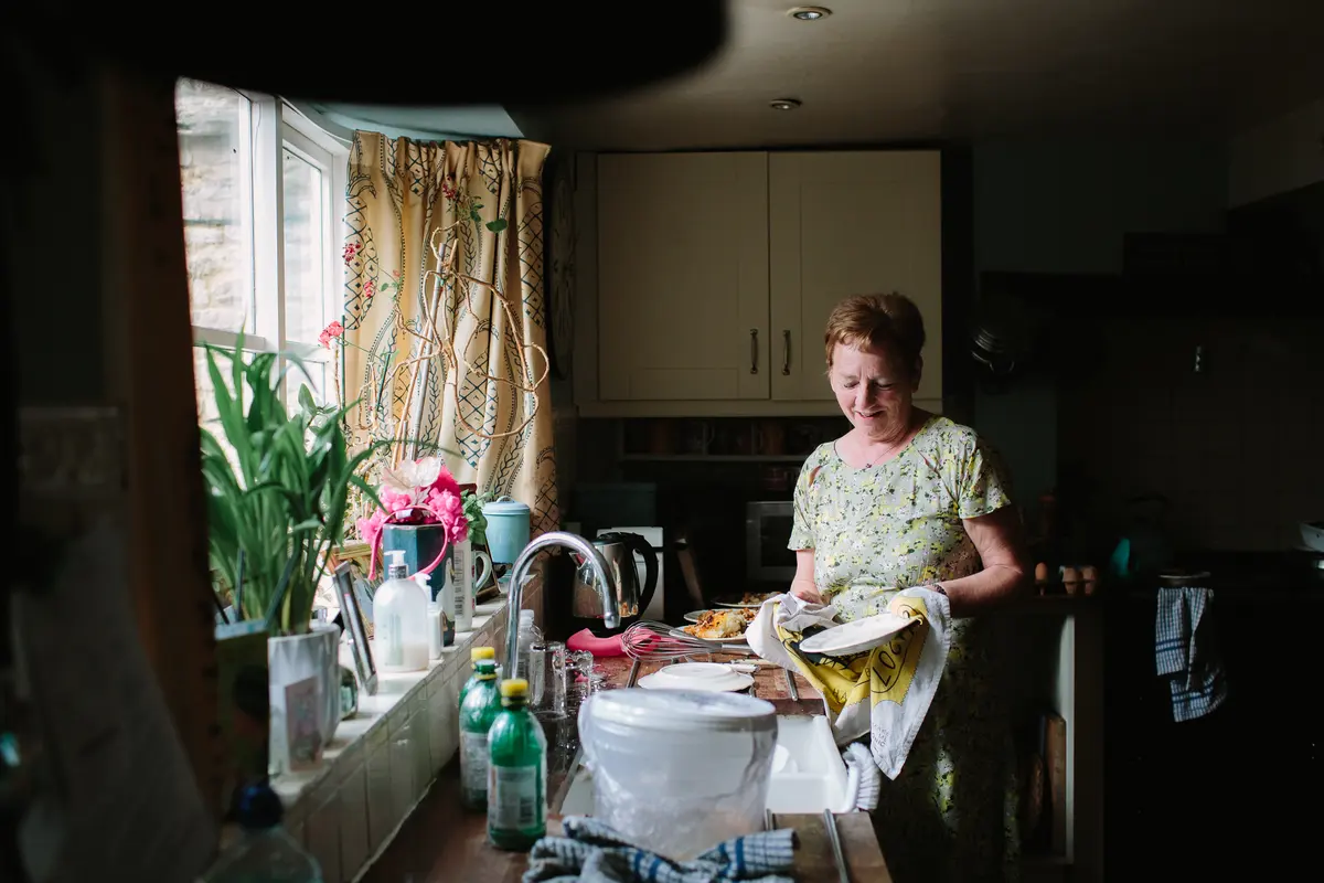 Woman drying plates with a tea towel at the kitchen sink on the wedding morning