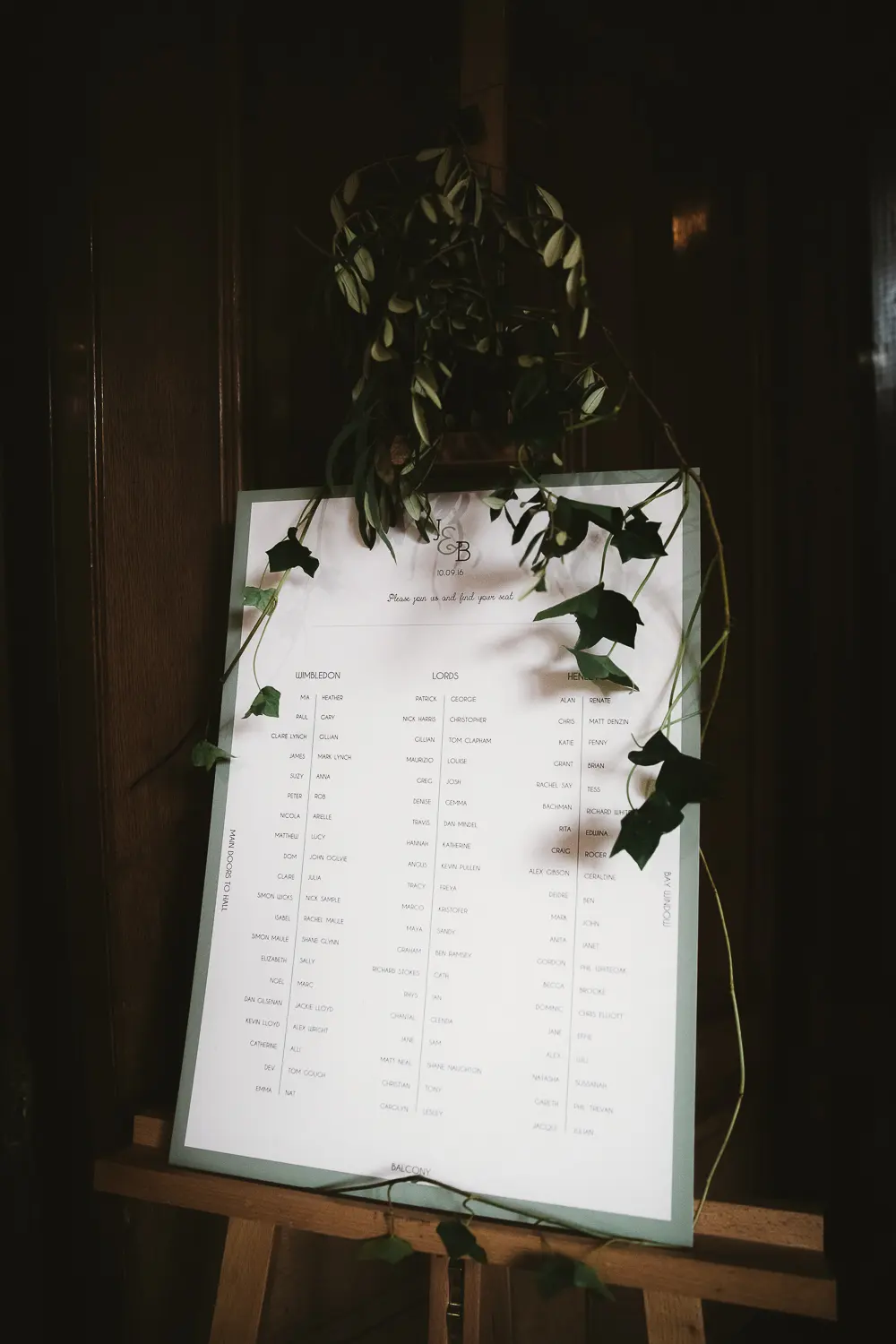 Seating plan on a wooden easel draped with trailing ivy against dark panelling