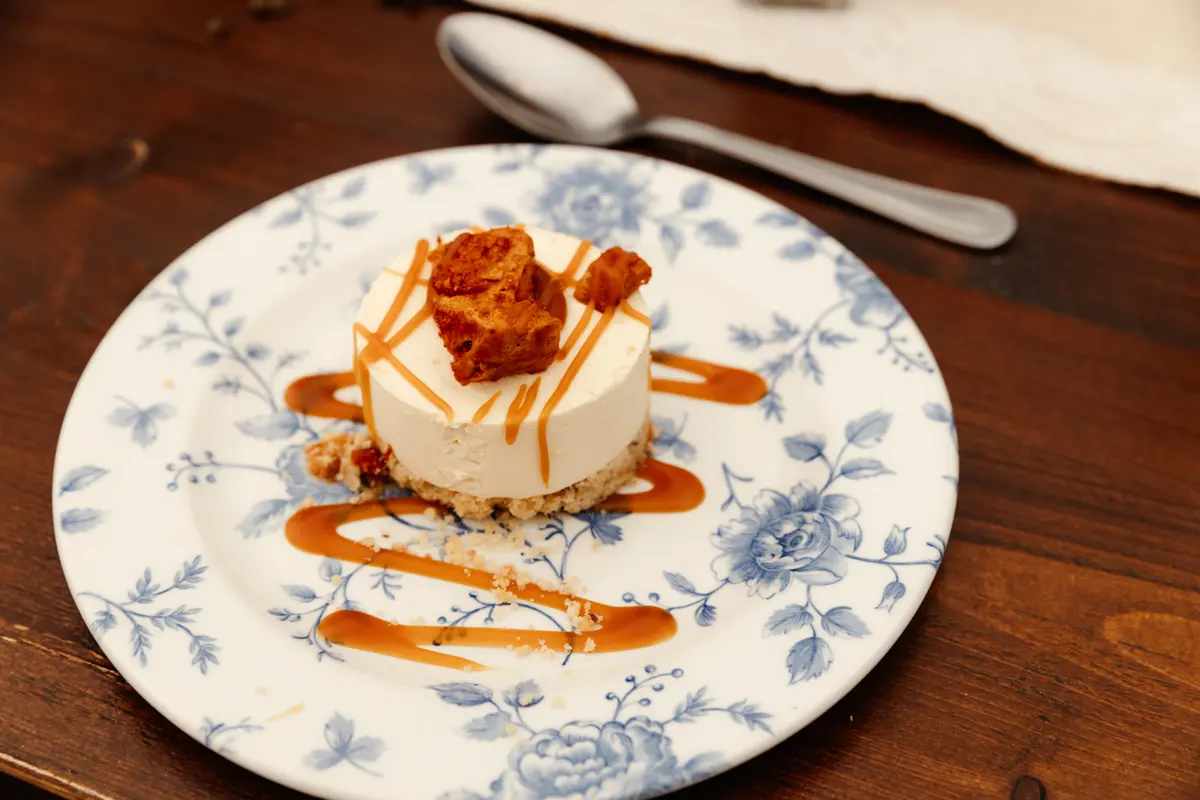 Cheesecake with caramel sauce and honeycomb on a blue and white floral plate