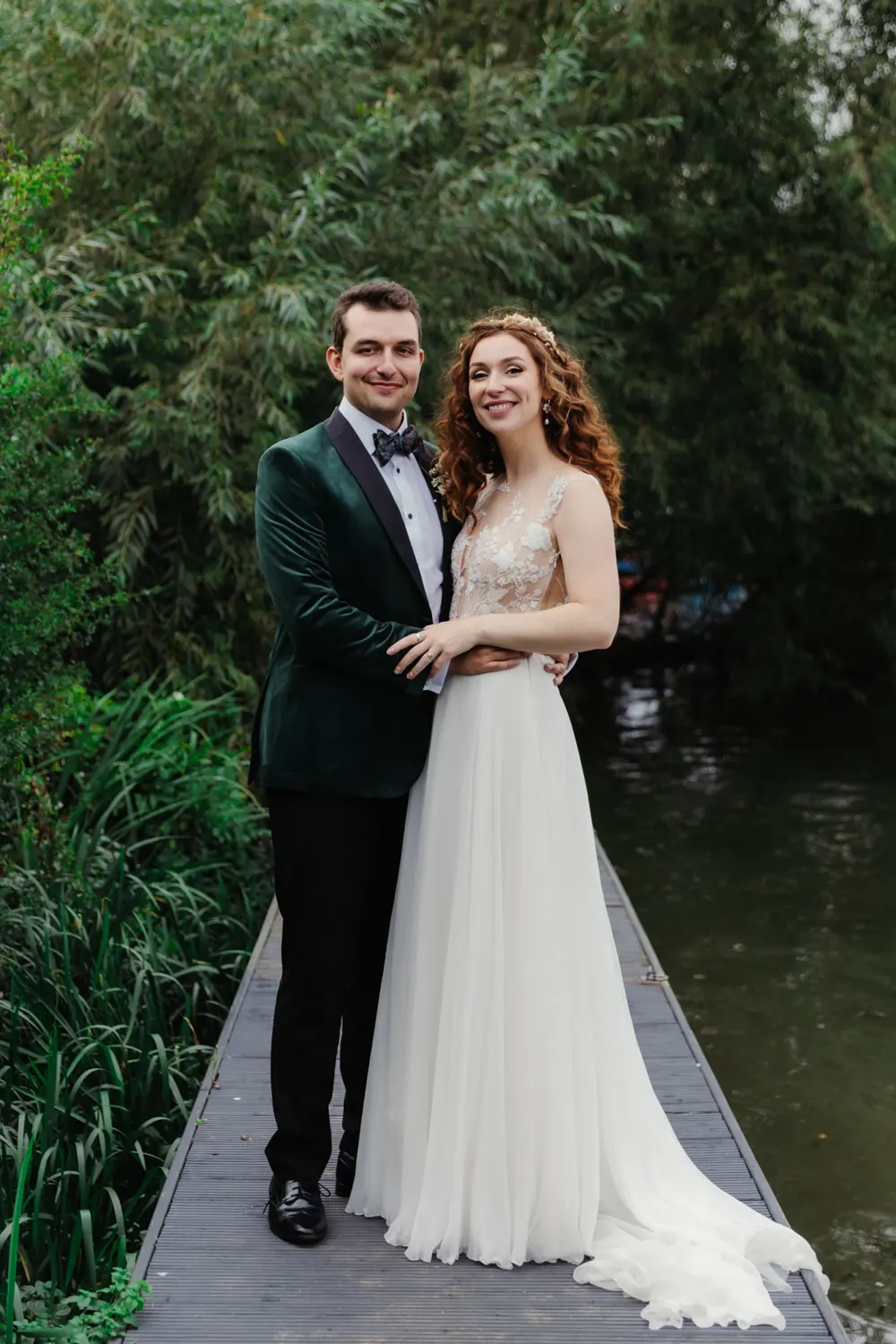 Bride and groom embracing on a wooden jetty beside the river at the Perch
