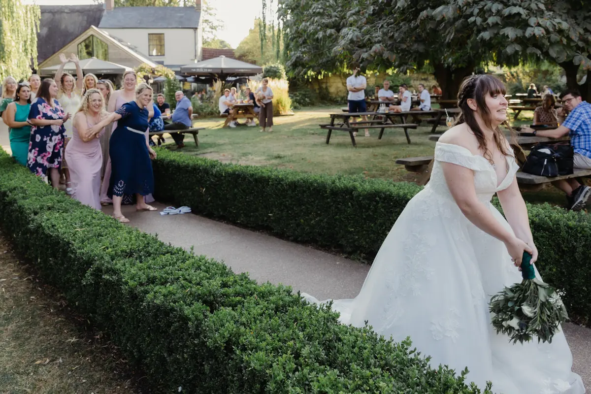 Bride throwing her bouquet to waiting guests in the garden at the Perch