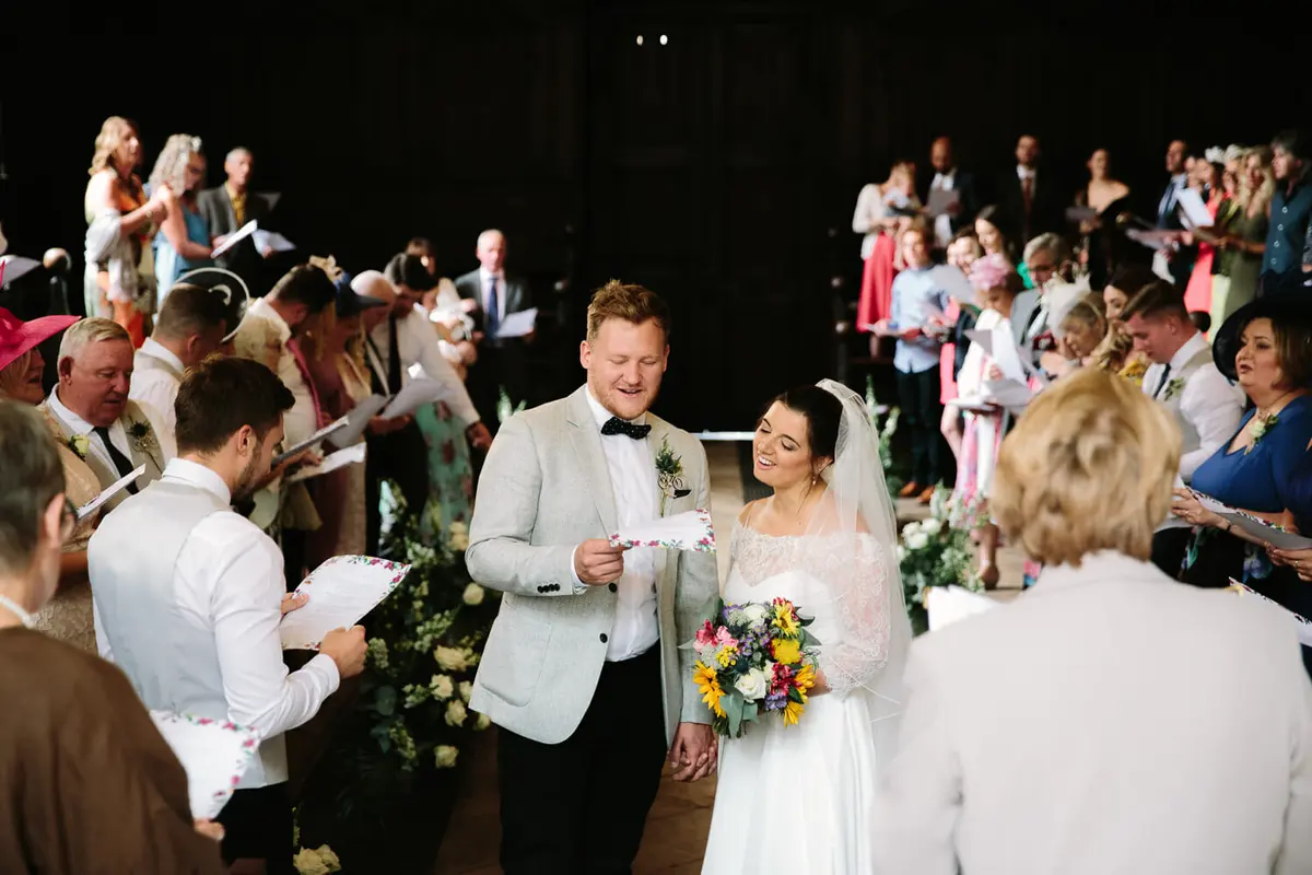 Bride and groom singing with their guests during ceremony at the Bodleian Library Oxford