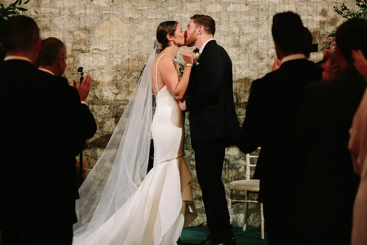 Bride and groom first kiss during ceremony at Manor Farm Barn Wedding venue