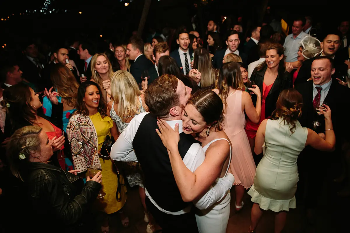 Bride and groom hugging in the middle of cheering guests on the dance floor