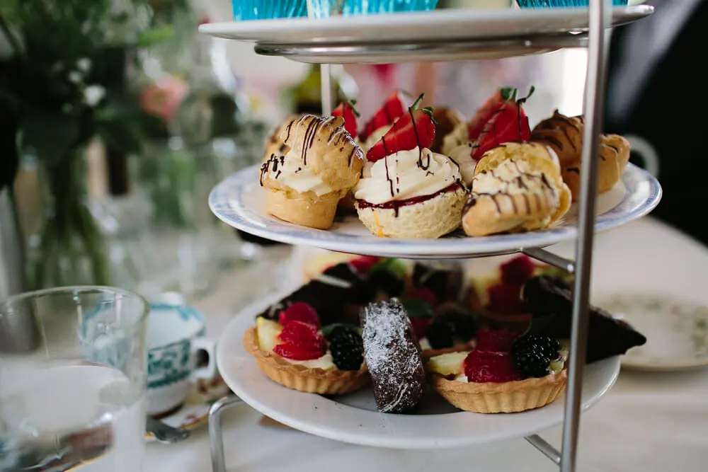 Cake stand of profiteroles with strawberries, fruit tarts and chocolate cakes on a tea table
