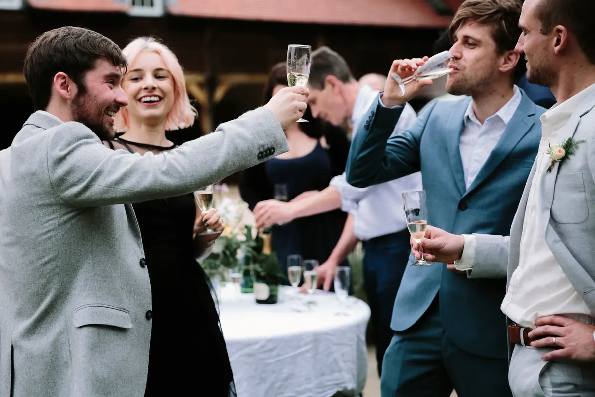 Guests raising glasses of champagne in a toast at the outdoor drinks reception