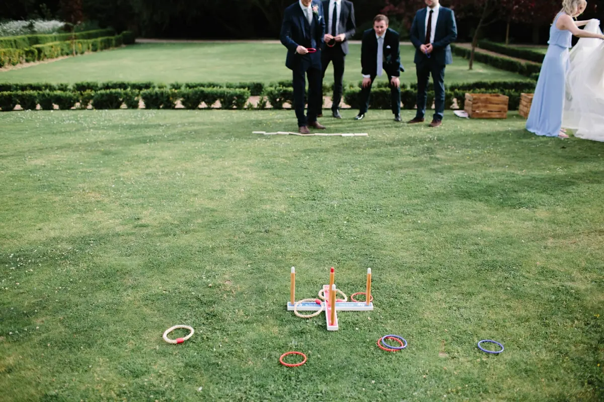 Guests in suits playing a lawn hoopla game in a formal garden