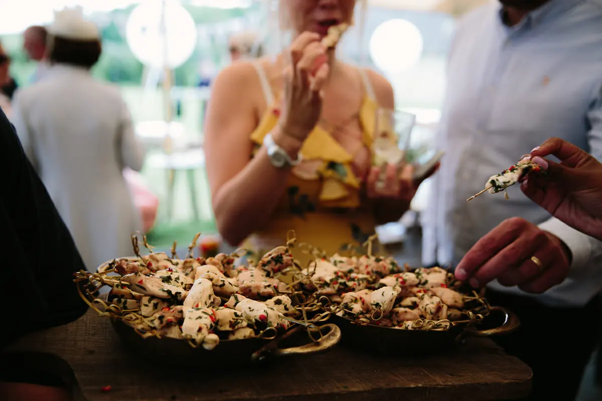 Guests taking chicken skewers from copper pans at the drinks reception