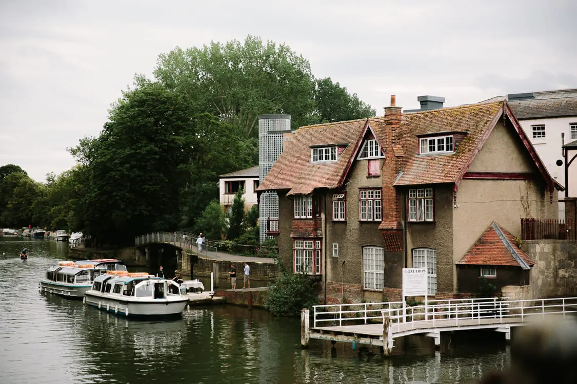 Boats moored on the River Thames beside a tall gabled brick house near Folly Bridge, Oxford