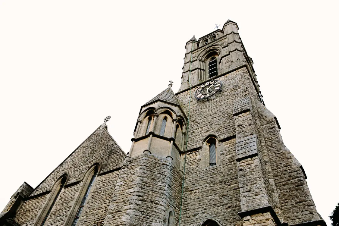 Looking up at the stone tower and clock of a Victorian chapel in Oxford