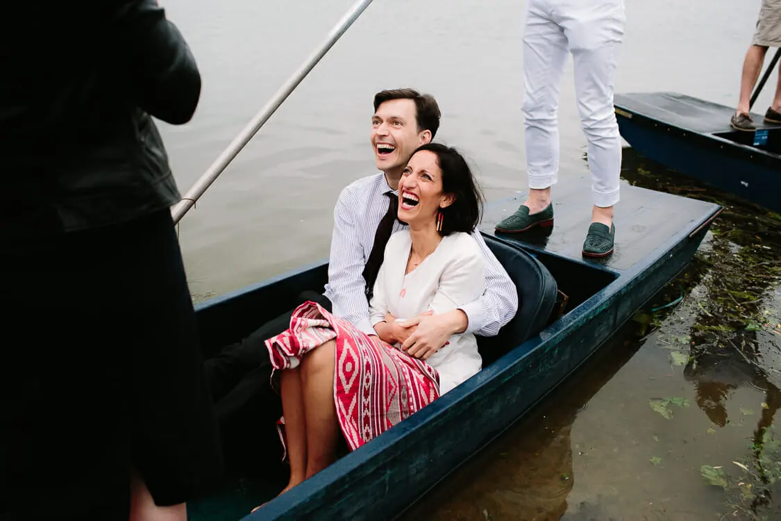 Two laughing guests cuddled up in a punt on the river at the Perch