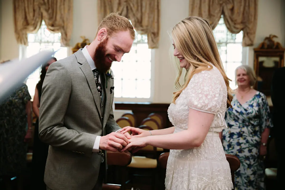 Groom placing the ring on the bride's finger during the register office ceremony