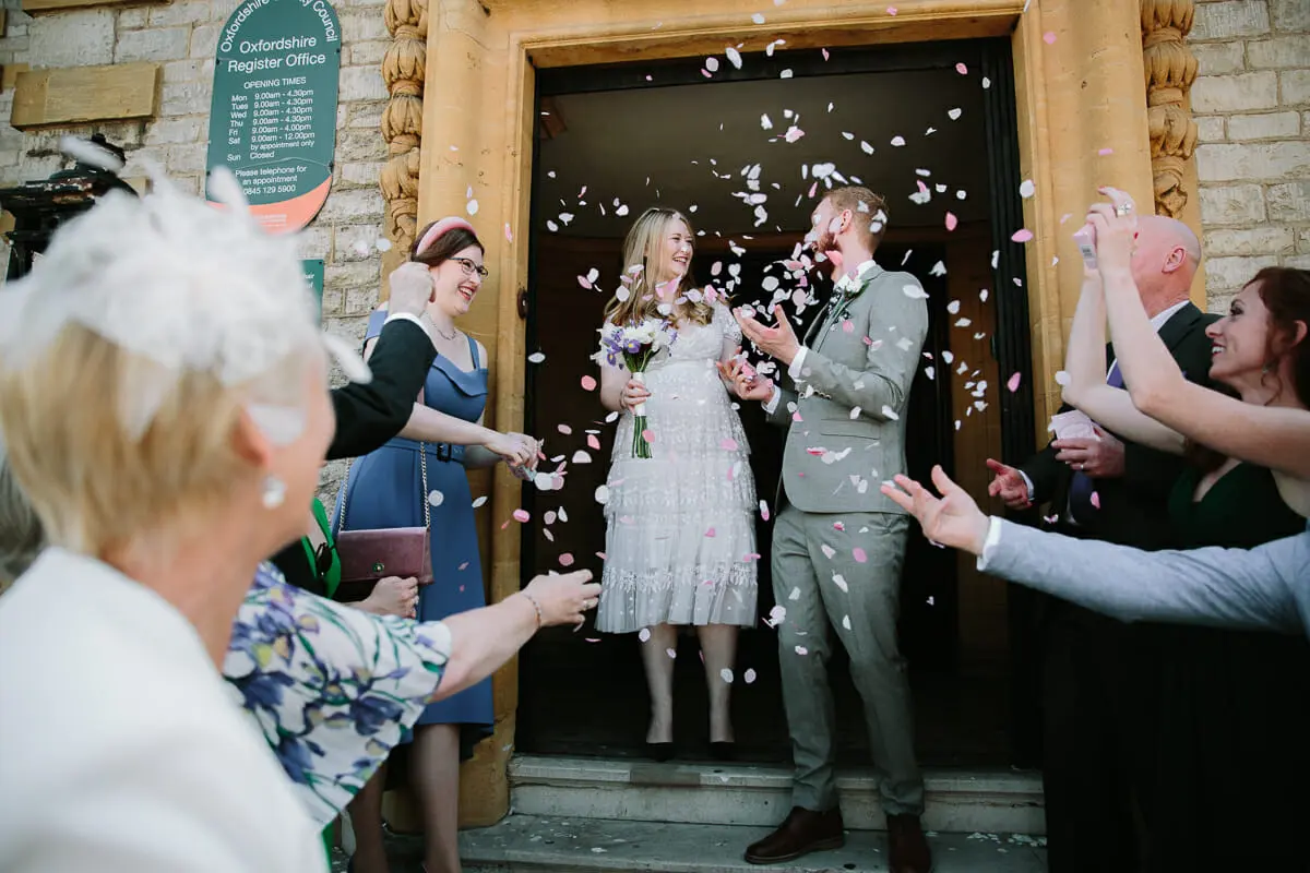 Guests throwing confetti over the bride and groom outside the Oxfordshire Register Office