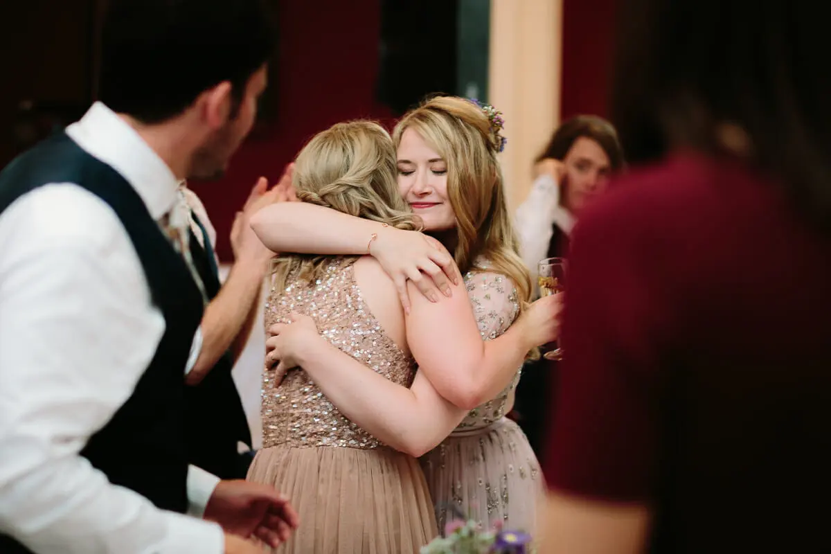 Bride embracing a bridesmaid in a sequinned dress after the speeches
