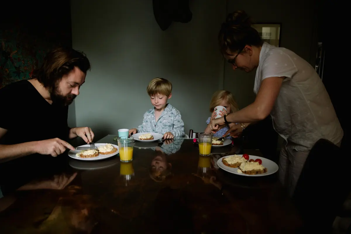 Family eating breakfast together around a dark wooden kitchen table