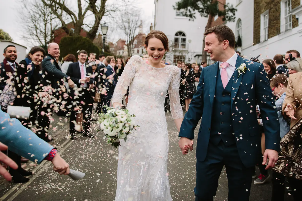 Bride and groom walking hand in hand through a shower of confetti on a London street