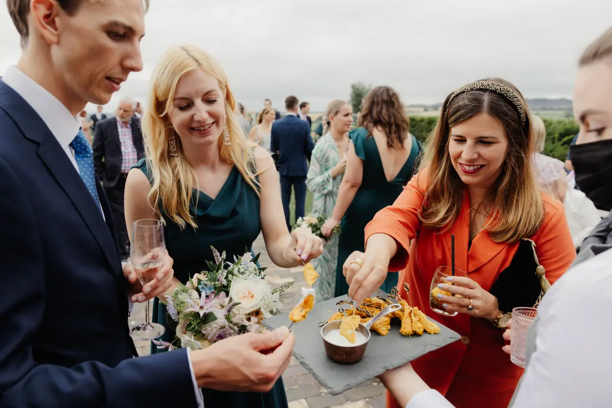 Guests picking canapes from a slate board during the drinks reception at Primrose Hill Farm
