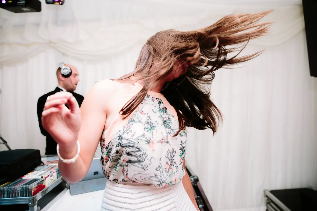 Guests dancing at wedding with DJ in background