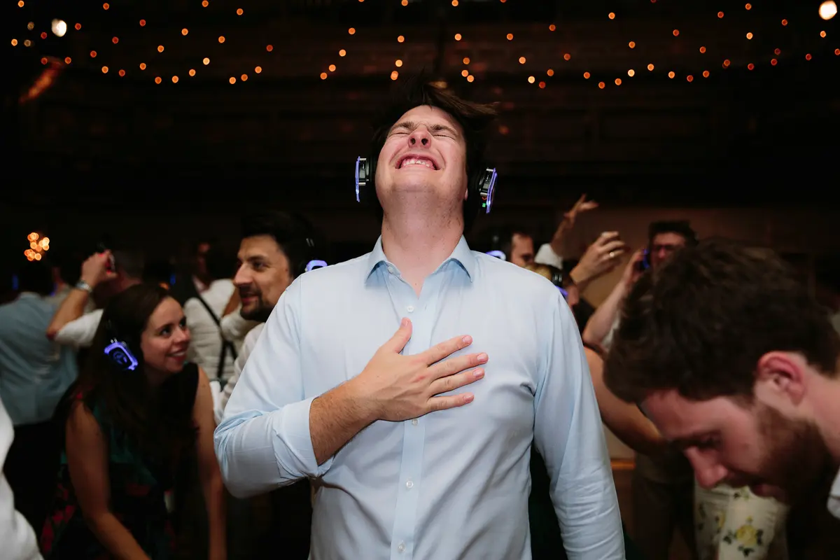 Guest in a silent disco headset singing with his eyes shut and hand on his heart