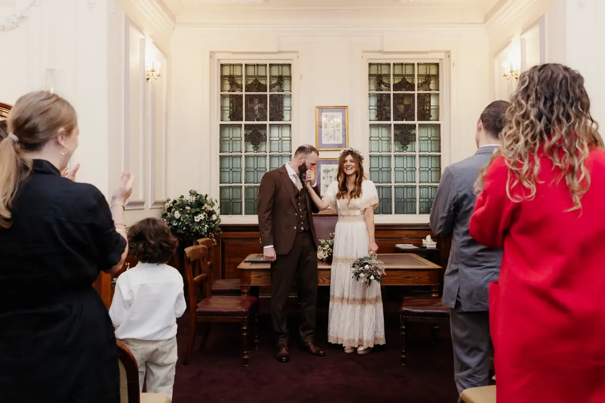 Groom wiping his eyes beside the bride as guests applaud at the end of the ceremony