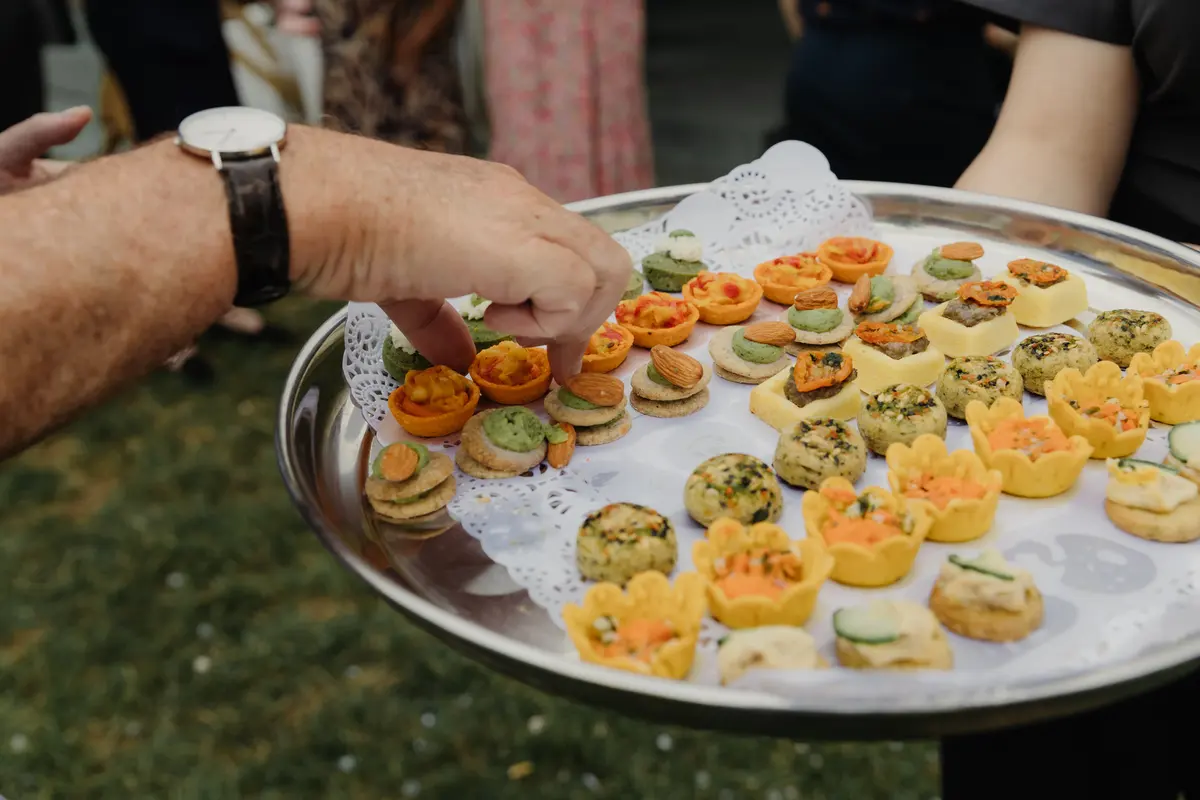 Guest taking a canape from a silver tray of tartlets and bites at the drinks reception