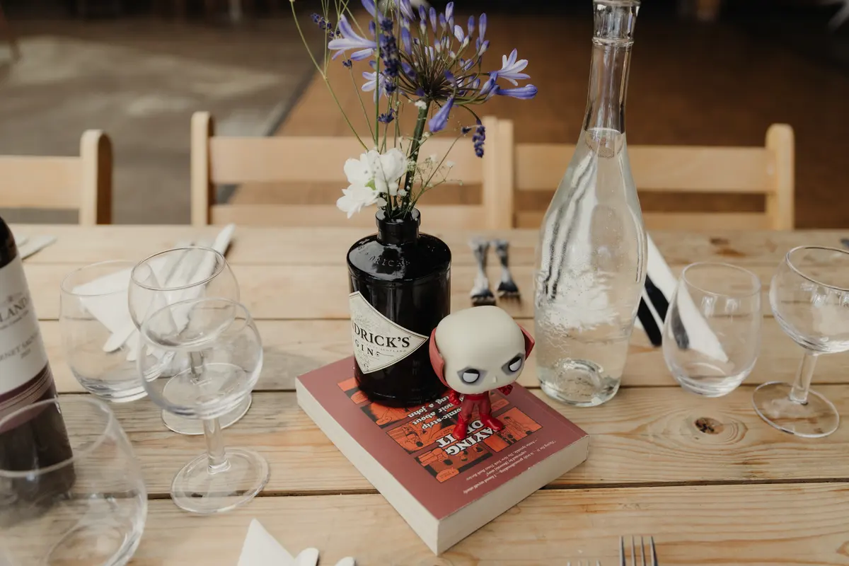 Table set with a gin bottle vase of agapanthus, a toy figure and a book at the Isis Farmhouse