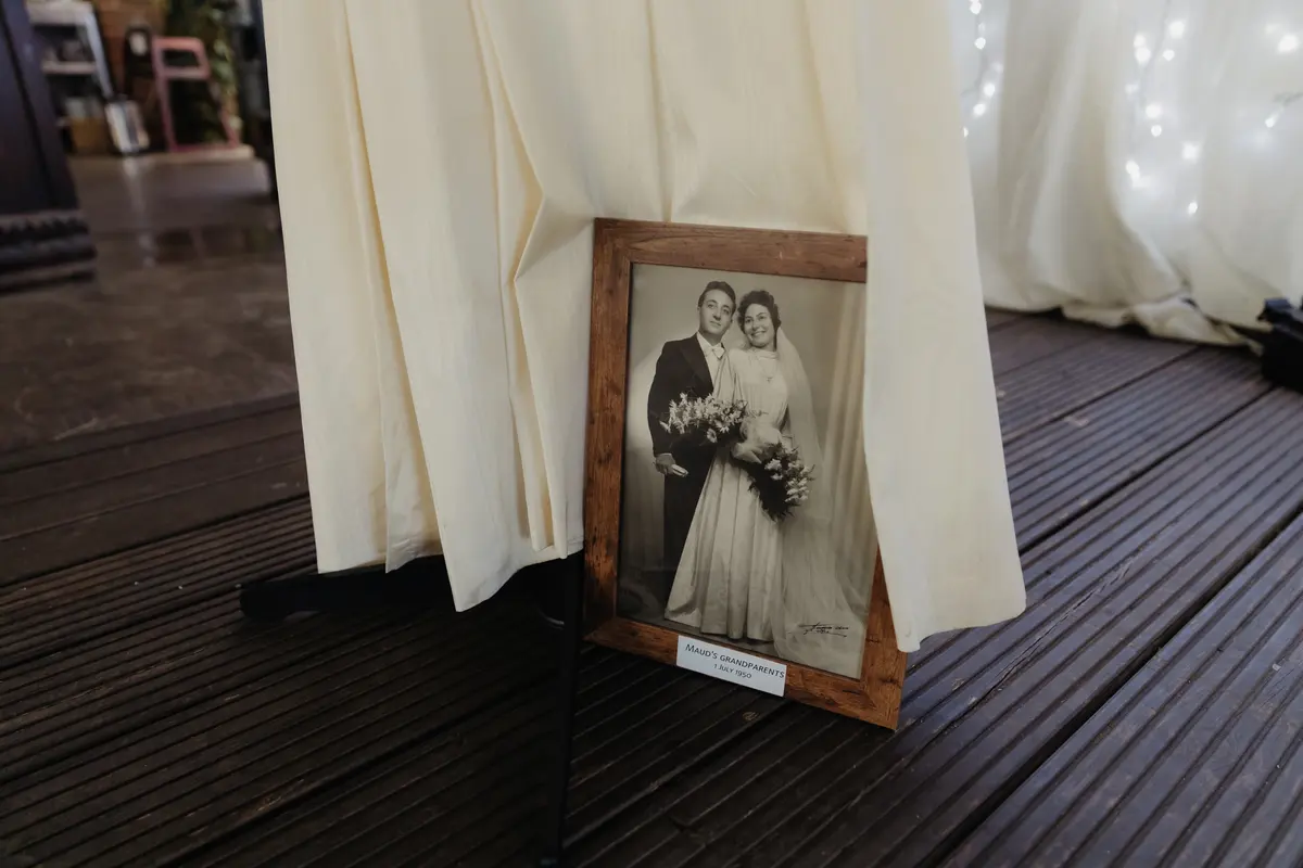 Framed black and white wedding photograph of a couple propped against a draped table at the Isis Farmhouse